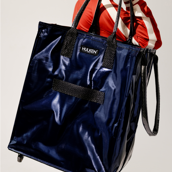 Person walking with a blue tote bag in hand